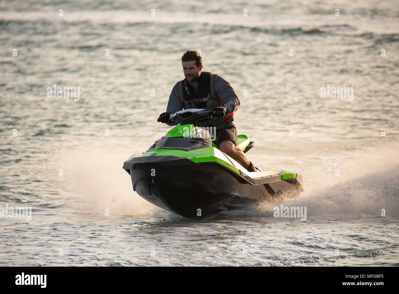 Homme d'âge moyen portant un gilet de vie conduit une motomarine Jet ski le long d'une mer calme. Banque D'Images