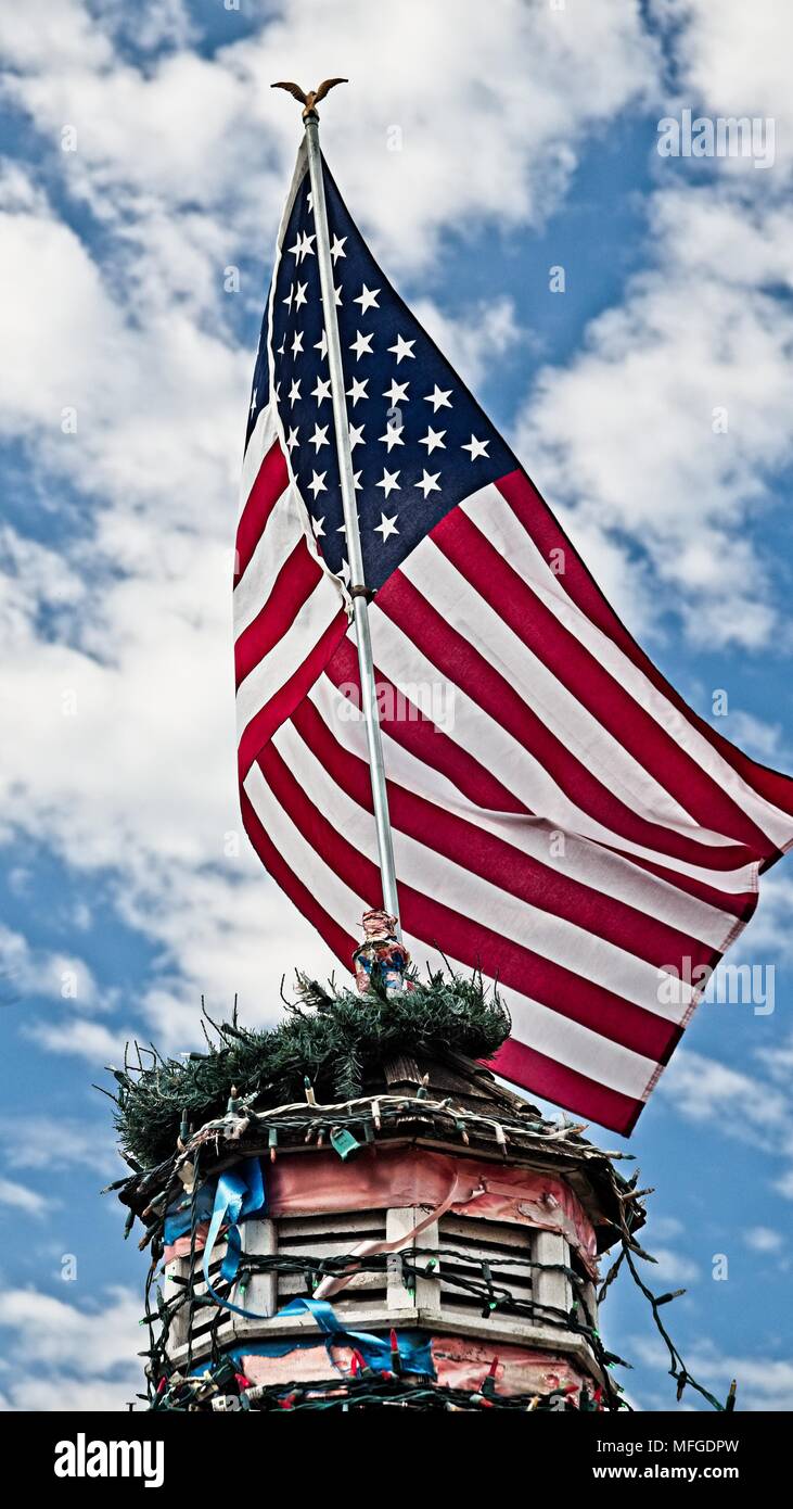 Drapeau américain au sommet d'un bâtiment avec des lumières d'arbre de Noël dans Old Town Spring TX Banque D'Images