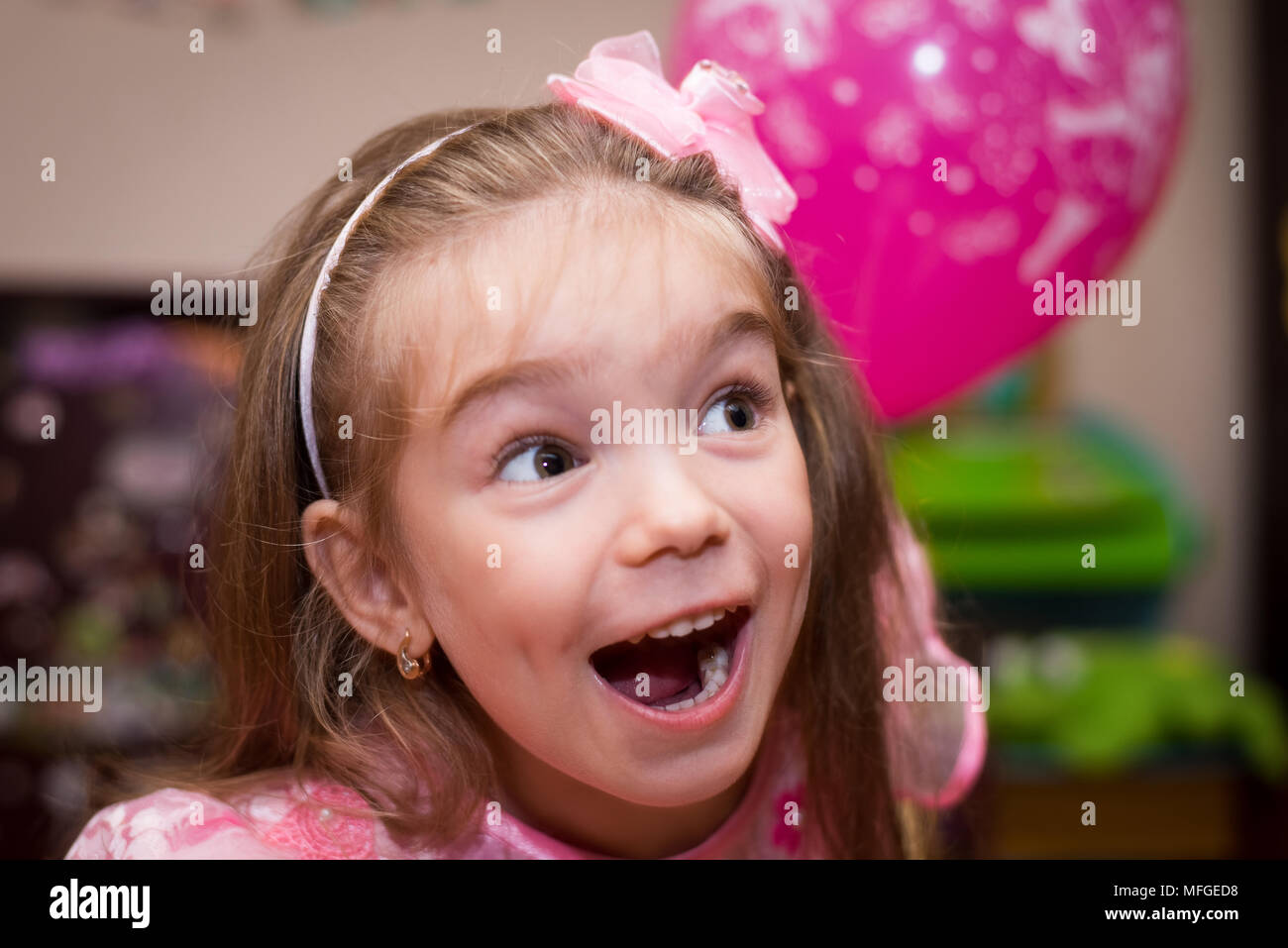 Petite fille dans une belle robe rose avec une balle dans la chambre des enfants Banque D'Images
