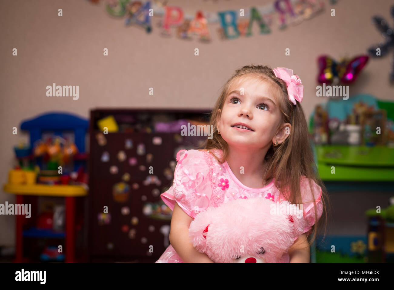 Petite fille dans une belle robe rose avec des jouets dans la chambre des enfants Banque D'Images