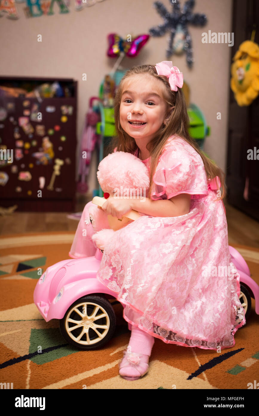 Petite fille dans une belle robe rose de poser dans une chambre d'enfants avec jouets Banque D'Images