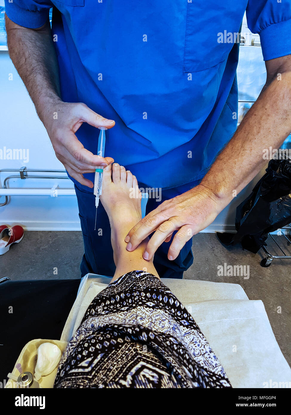 Un médecin est l'injection de l'anesthésique local dans le pied des patients en préparation à la chirurgie d'un oignon du tailleur. Banque D'Images