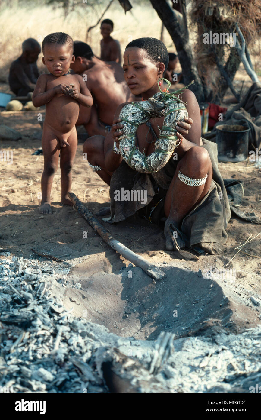 Femme BUSHMEN Python pour la cuisine, regardé par enfant Banque D'Images