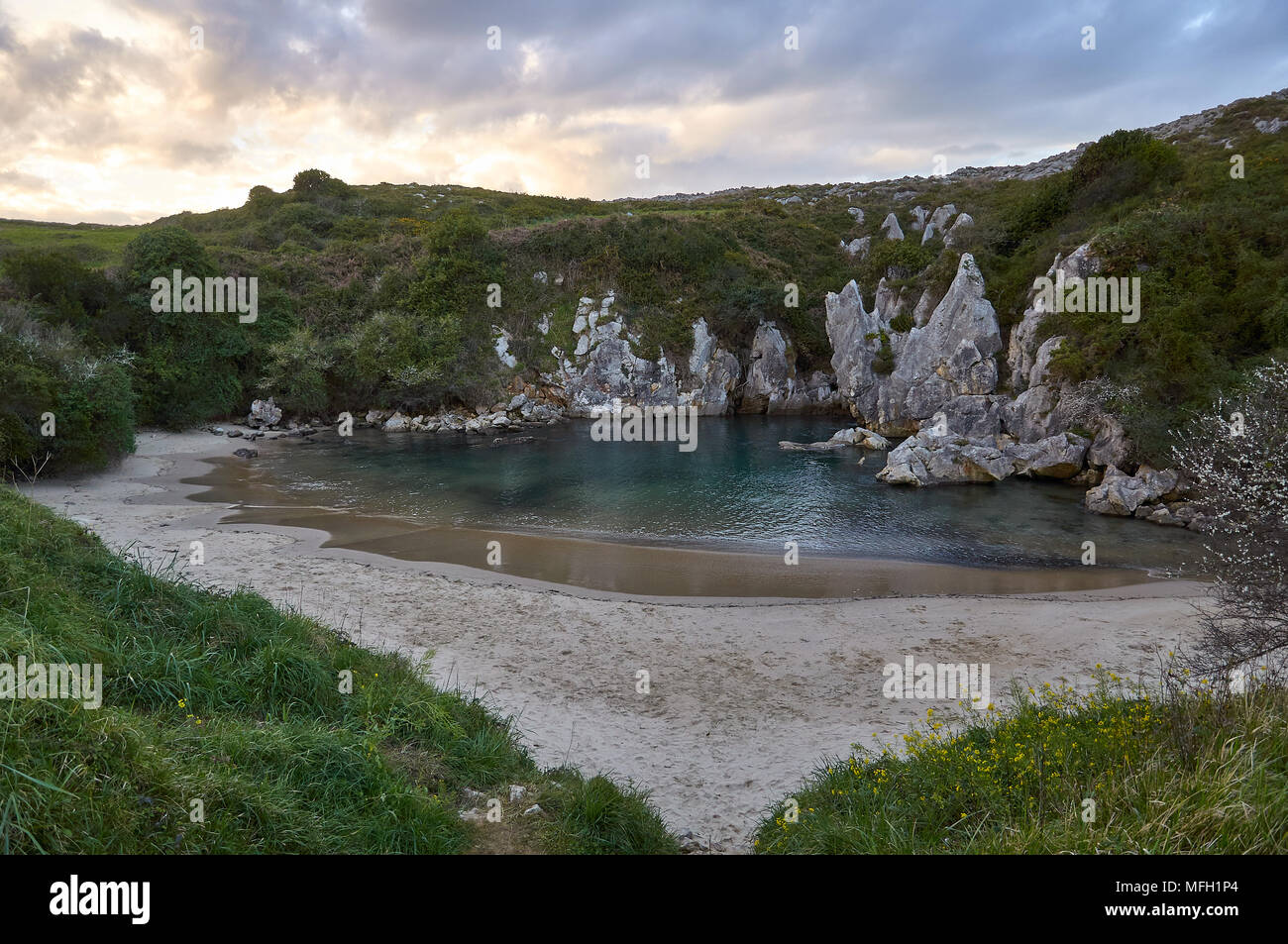 Coucher de soleil sur la plage de Gulpiyuri, qui est une plage intérieure, s'est produite dans un gouffre inondé créé par l'érosion karstique (mer de Cantabrian, Naves, Llanes, Asturies, Espagne) Banque D'Images