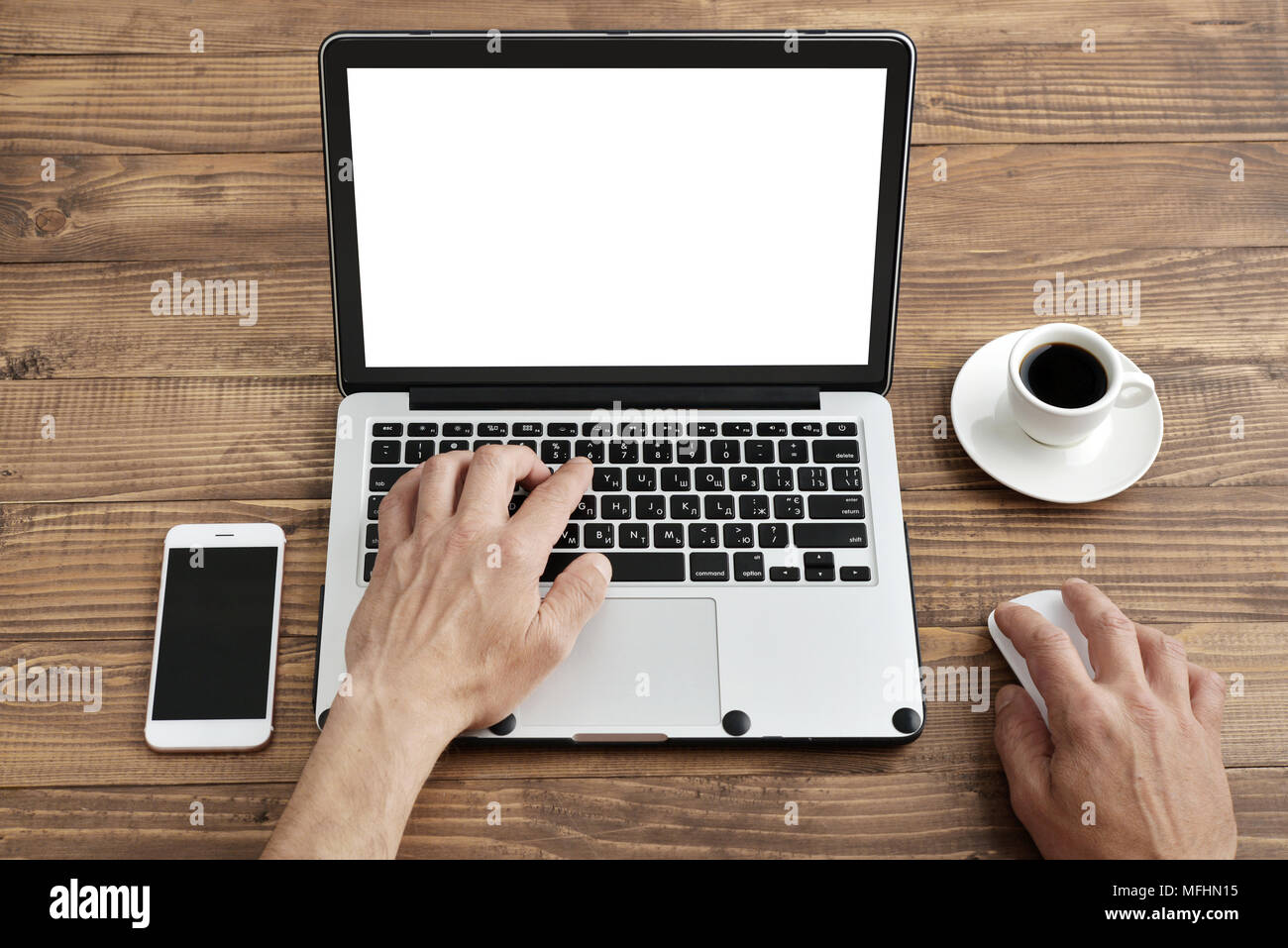 Vue de dessus de l'homme travaillant sur ordinateur portable portant sur le fond de bois avec tasse de café et smartphone Banque D'Images