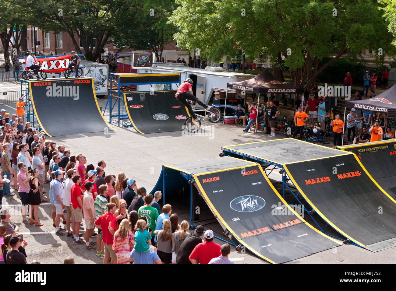 Une grande foule regarde un jeune pro BMX spectaculaire effectuer des tricks en l'pro compétition de BMX au crépuscule sur Critérium 25 avril 2015 à Athènes, GA. Banque D'Images