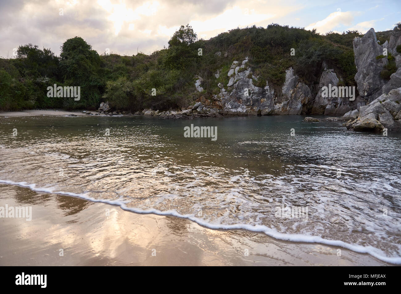 Coucher de soleil sur la plage de Gulpiyuri, qui est une plage intérieure, s'est produite dans un gouffre inondé créé par l'érosion karstique (mer de Cantabrian, Naves, Llanes, Asturies, Espagne) Banque D'Images