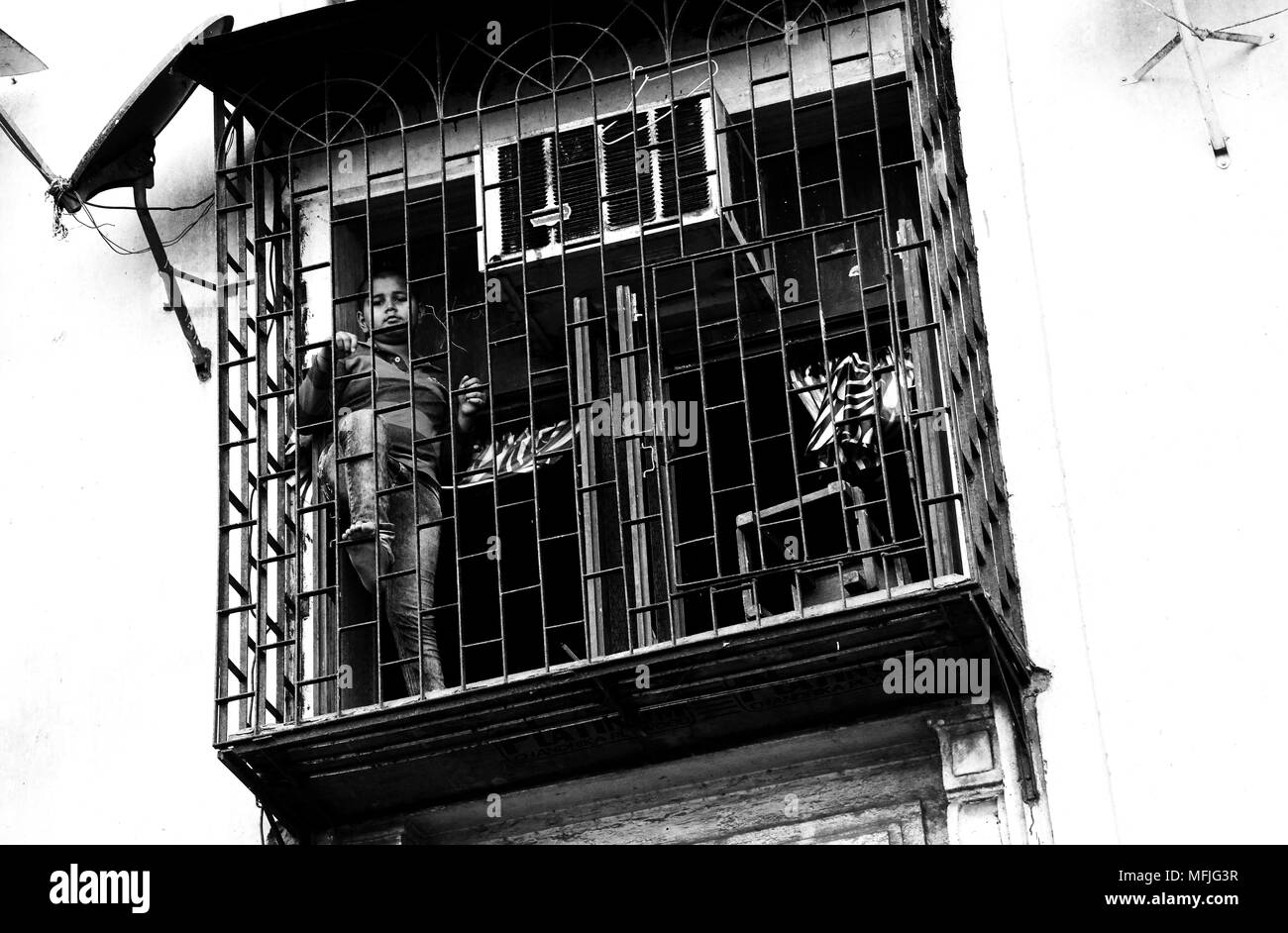 Jeune homme en voyant la rue en dessous de la cage balcon de sa maison, Margao, Nr, Benaulim Goa, Inde Banque D'Images