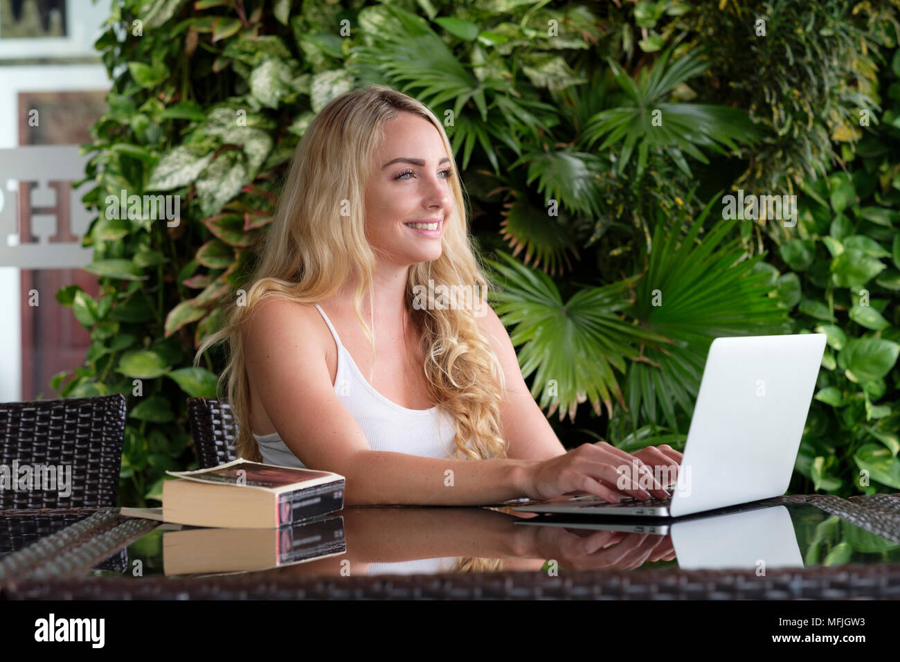 Young Caucasian woman backpacker portant un gilet blanc haut et assis à une table en Asie travailler sur un ordinateur portable, le Vietnam, l'Indochine, l'Asie du Sud-Est, Asie Banque D'Images