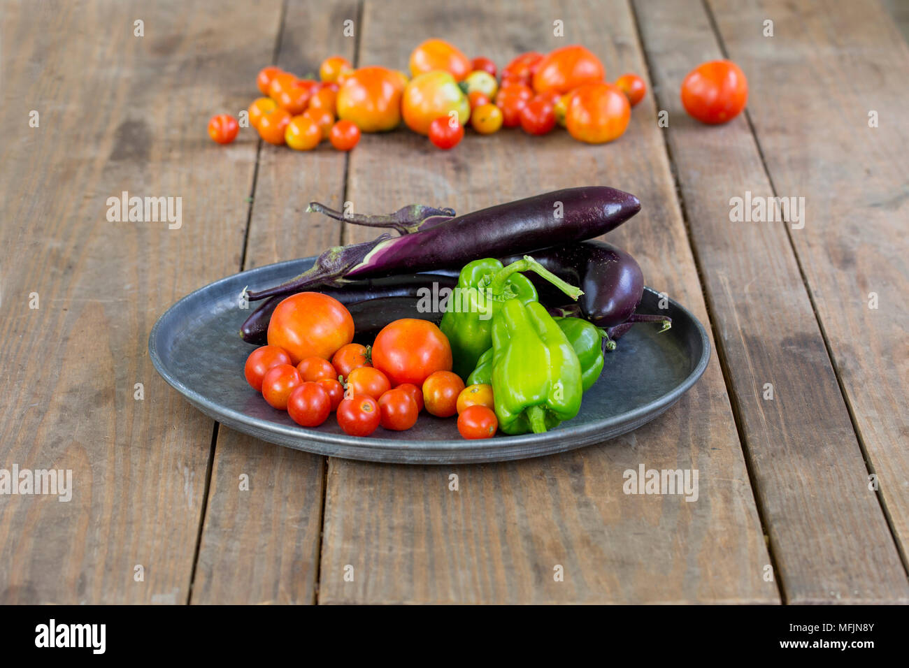 Une assiette de poivrons, aubergines et les tomates s'asseoir sur une table après avoir été pris à partir d'un jardin. Banque D'Images