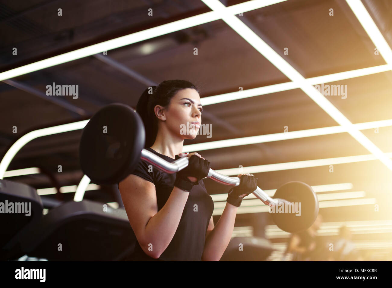 Jeune femme de remise en forme de l'exercice avec des barres en sport pour des muscles de bâtiment Banque D'Images