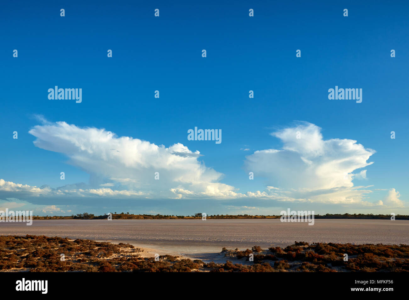 Ciel bleu vif contraste avec la faiblesse de l'approche avant la tempête sur un lac de sel sec. Banque D'Images