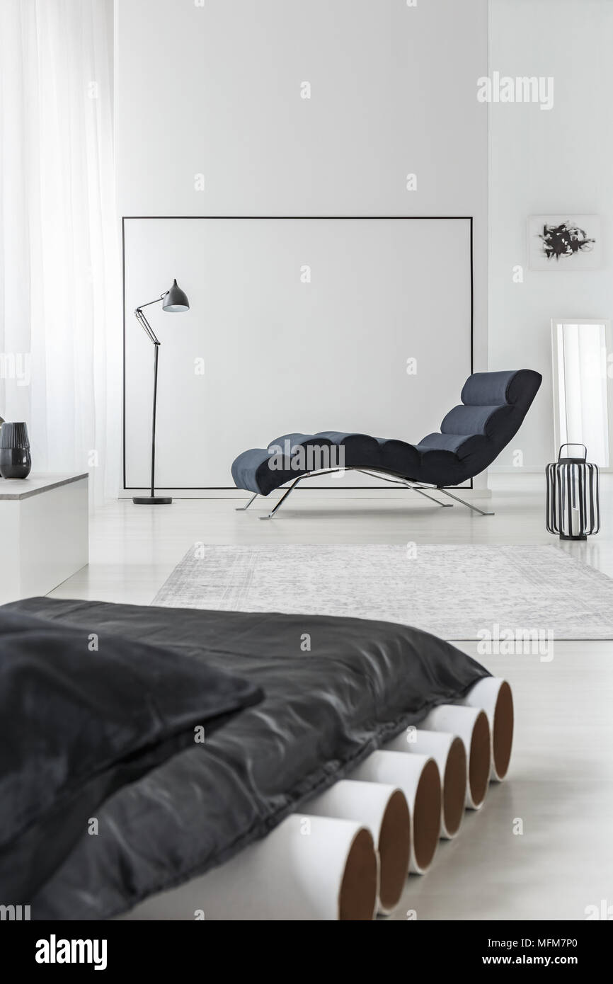Matelas noir sur blanc dans les tubes de l'intérieur chambre à coucher avec  chaise longue et carré sur le mur Photo Stock - Alamy