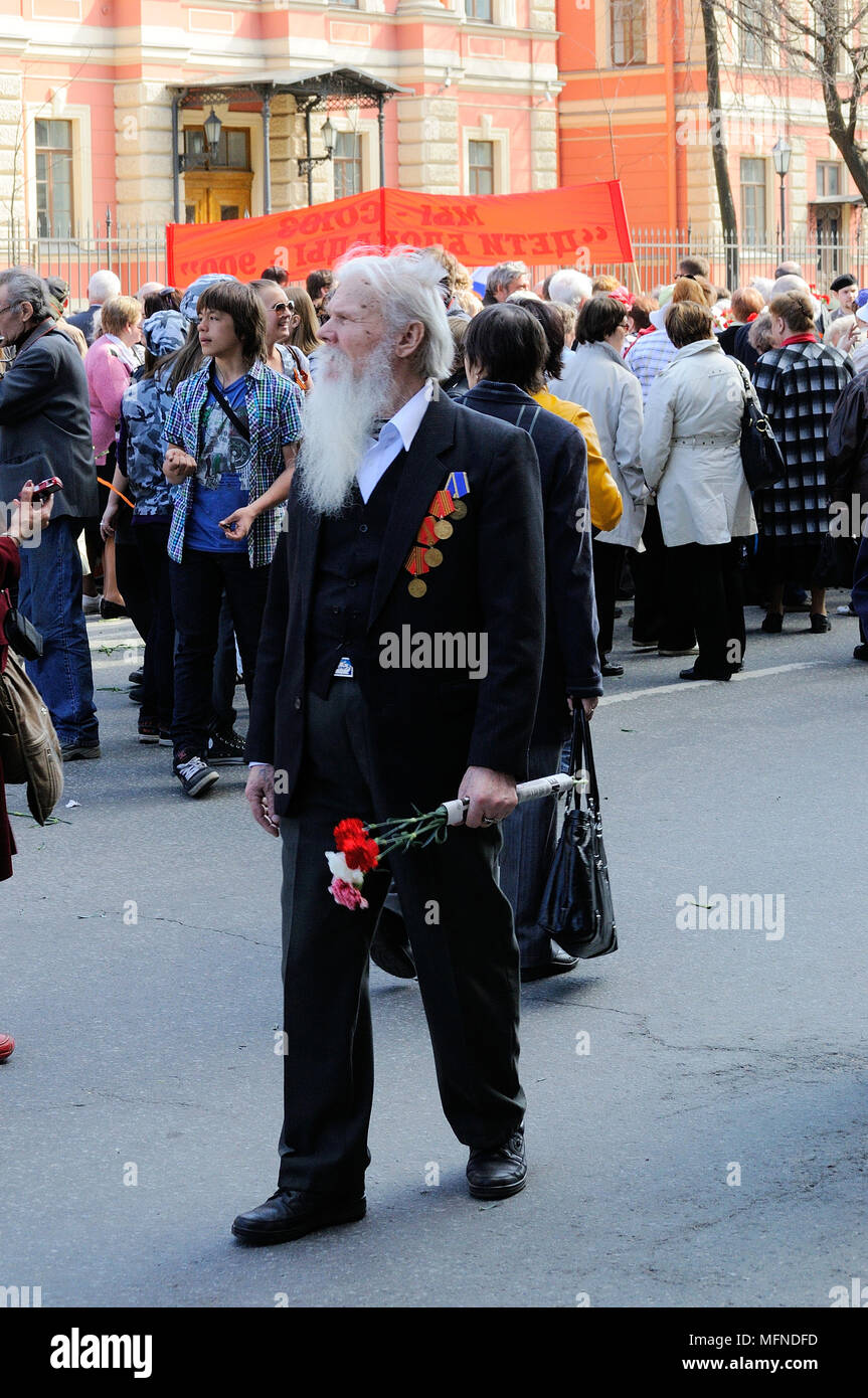 Un vieux vétéran, participant à la Seconde Guerre mondiale, avec des médailles, des ordres, des promenades sur la victoire de la journée, la Russie avec des fleurs dans les mains Banque D'Images