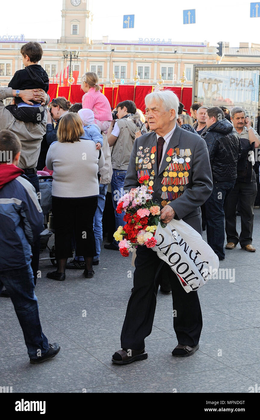Un vieux vétéran, participant à la Seconde Guerre mondiale, avec des médailles, des ordres, des promenades sur la victoire de la journée, la Russie avec des fleurs dans les mains Banque D'Images