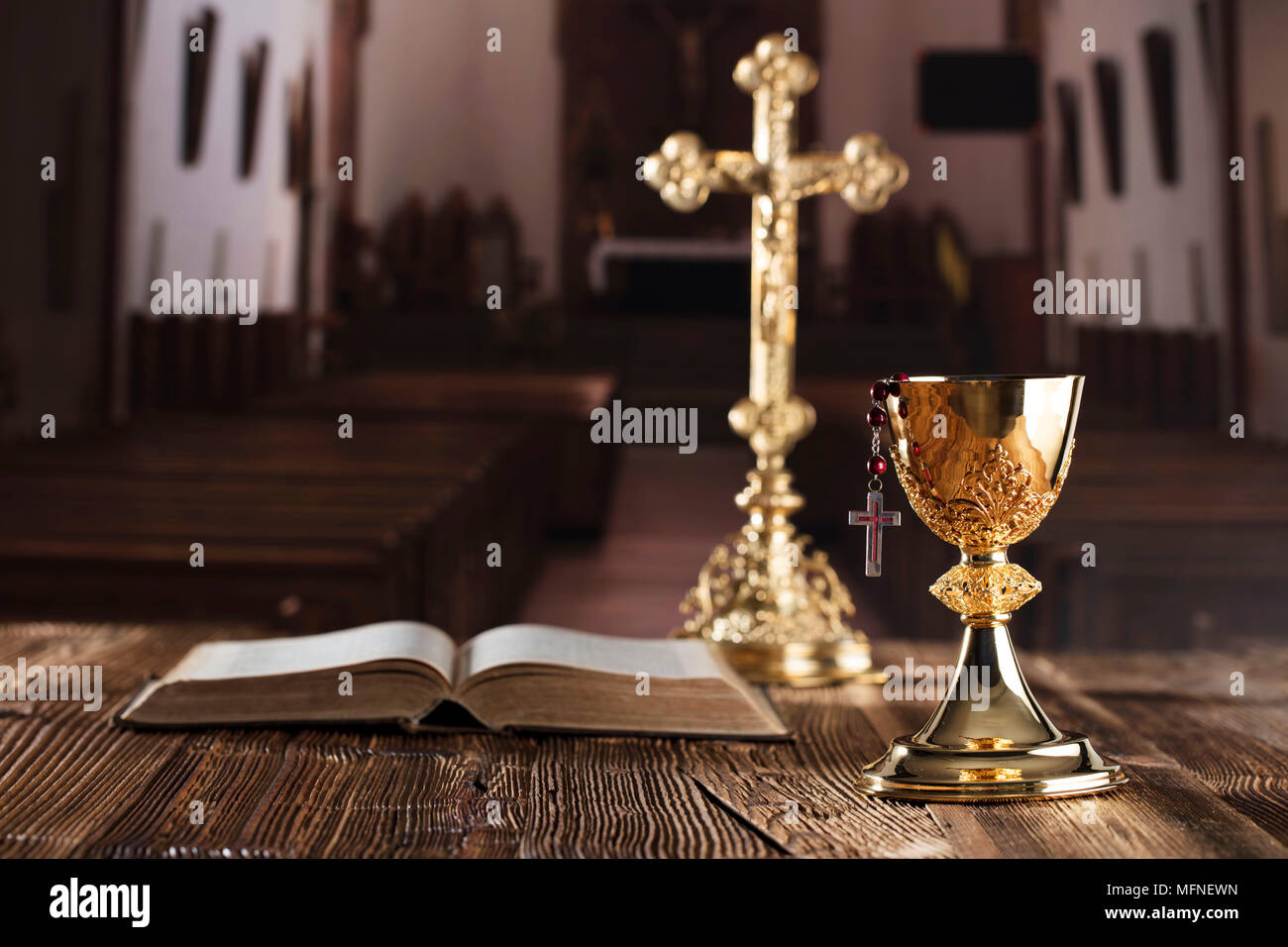 Première communion thème. La Croix, la Sainte Bible, Rosaire et Golden Chalice sur fond brun. Banque D'Images