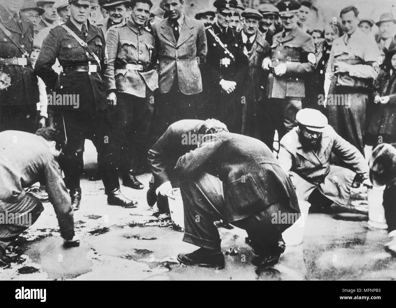 Nazis autrichiens et les habitants regardent le juifs sont forcés d'obtenir sur ses mains et genoux et frottez le pavé, 1938. Banque D'Images