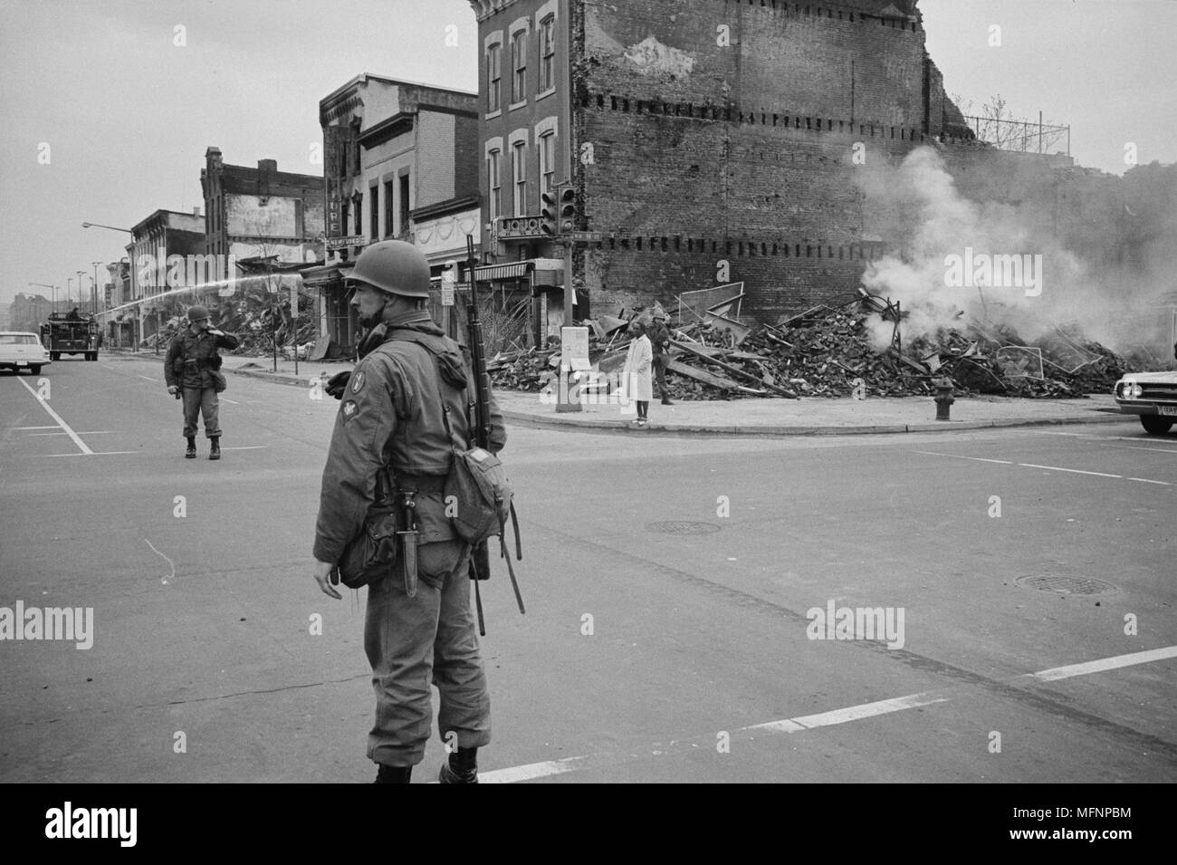 Soldat qui monte la garde dans une rue Washington, D.C., avec les ruines de bâtiments qui ont été détruits pendant les émeutes qui ont suivi l'assassinat de Martin Luther King Jr., 8 avril 1968. Photographe : Warren K Leffler. Banque D'Images