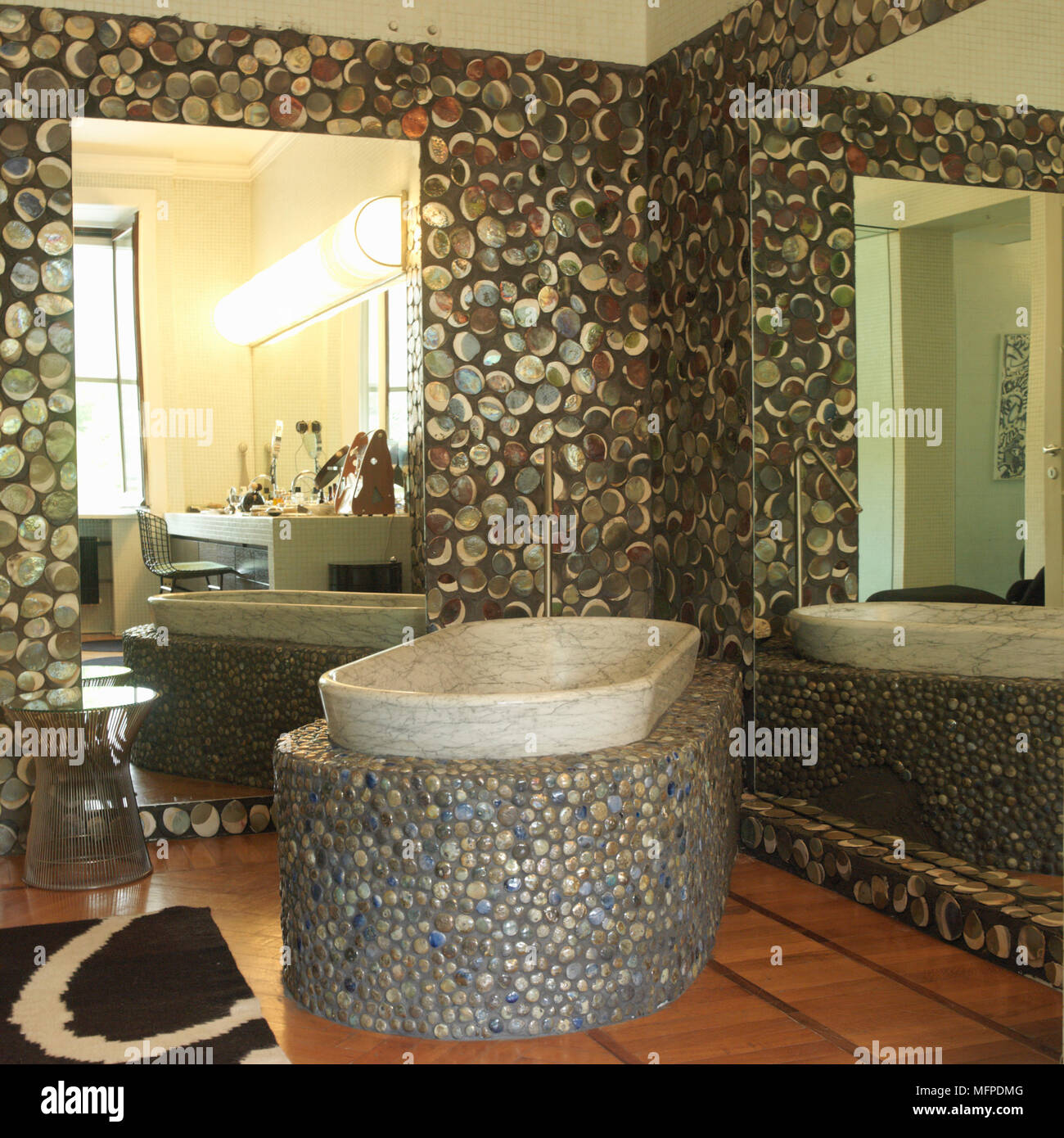 Un résumé et de galets d'effet pierre salle de bains avec double miroir et  baignoire en marbre situé dans la base de galets qui sur le plancher en  bois avec tapis abstrait