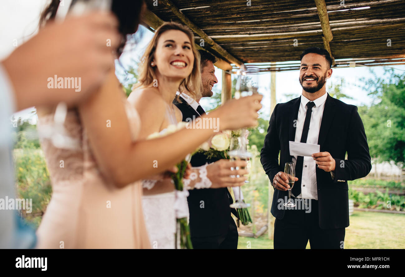 Best man performing discours pour toast à réception de mariage. Mariée et le marié de l'écoute d'un discours à leur réception de mariage. Banque D'Images Best man performing discours pour toast à réception de mariage. Mariée et le marié de l'écoute d'un discours à leur réception de mariage. Banque D'Images