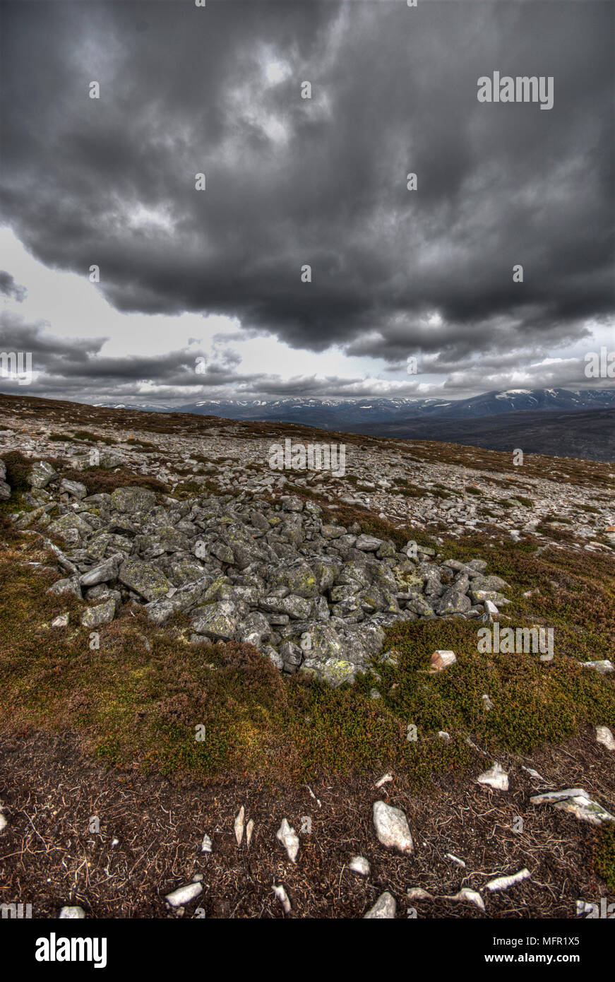 Vue de Morrone hill vers munros Highland avec cimes enneigées visibles contre ciel dramatique typique snd rochers et végétation au printemps. Banque D'Images
