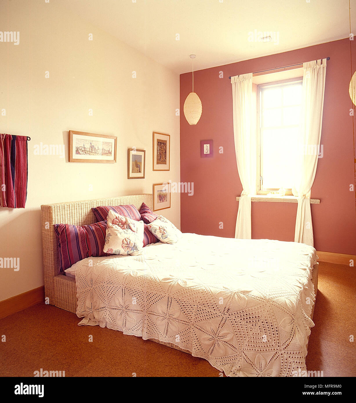 Chambre pays neutre et des murs roses couvre-lit blanc coussins coussins à motifs d'images encadrées, la lumière de la fenêtre Spotlight encastré au plafond Banque D'Images