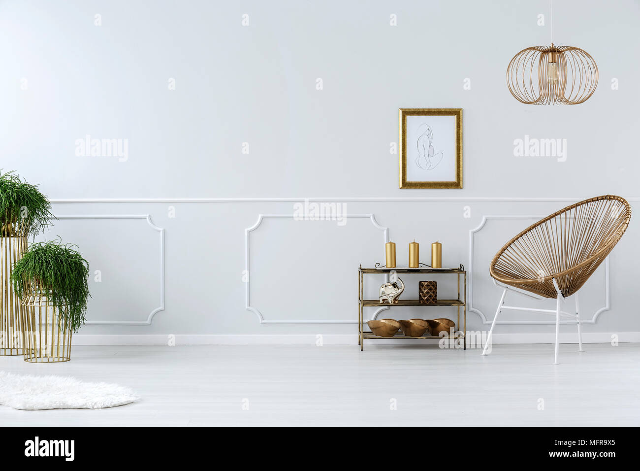 Wicker Chair moderne et dessin dans cadre doré sur fond blanc, mur vide dans un élégant salon intérieur Banque D'Images
