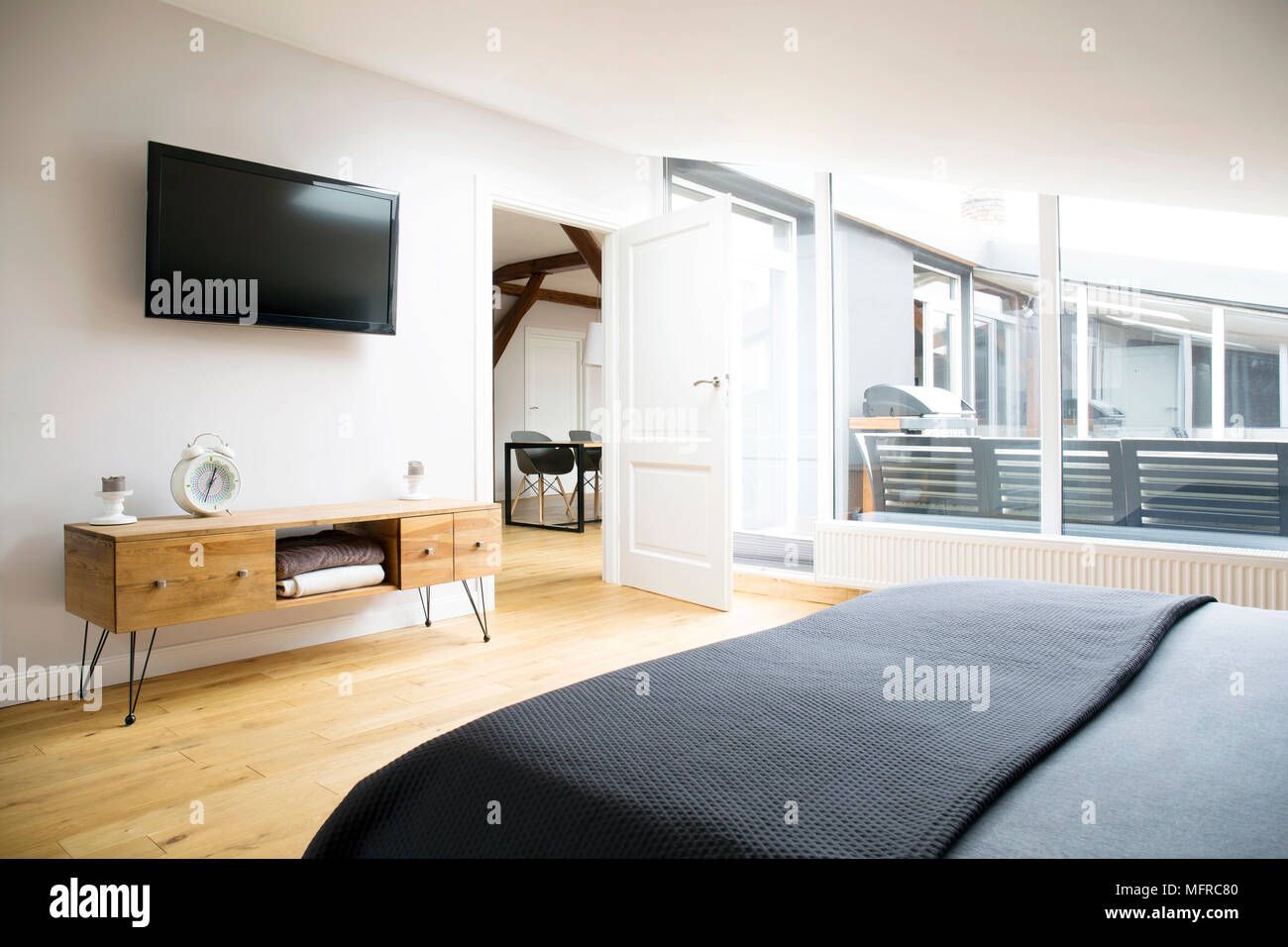 Vue latérale de l'intérieur chambre à coucher avec TV, armoire en bois et  grande fenêtre dans l'appartement Photo Stock - Alamy