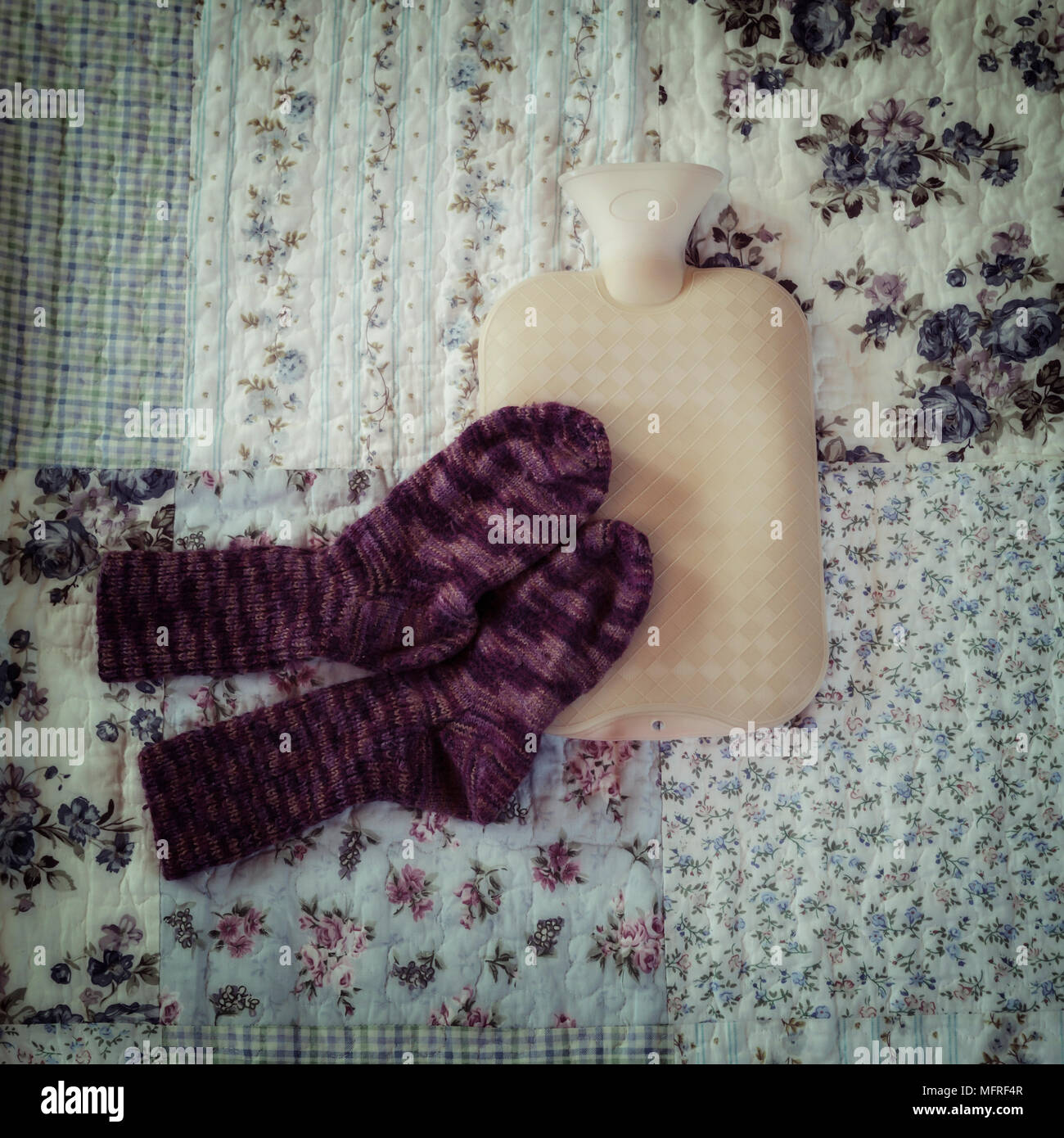 Bouteille à eau chaude avec des chaussettes tricotées main sur un lit vintag Banque D'Images
