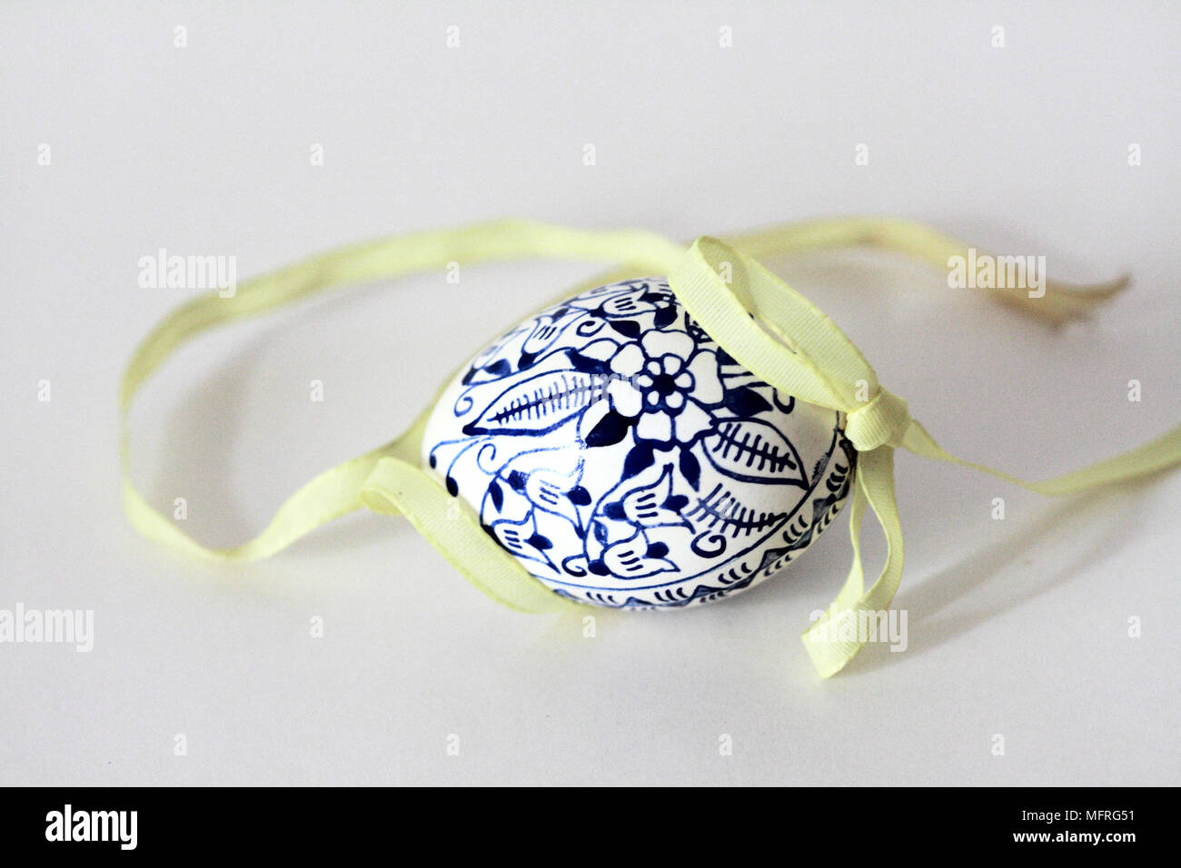 Tchèque traditionnel unique œuf de Pâques avec motif oignon bleu et jaune ruban sur un arrière-plan uni, blanc. Les oeufs sont décorés avec de l'encre et de cobalt Banque D'Images