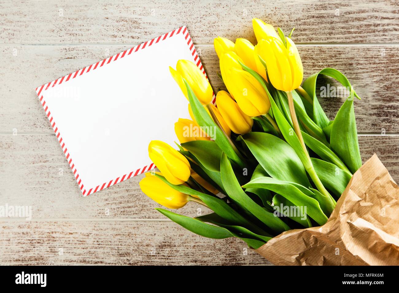 Une lettre et de tulipes jaunes sur fond de bois Banque D'Images