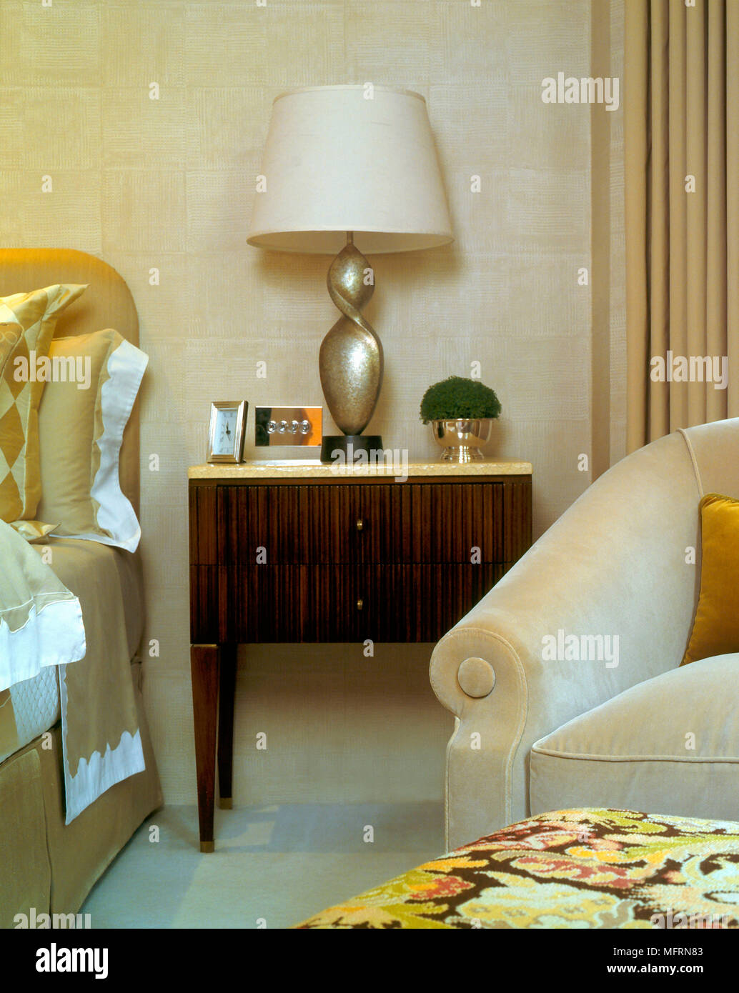 Un détail d'une chambre à coucher moderne en bois lit commode chevet lampe  fauteuil capitonné Photo Stock - Alamy