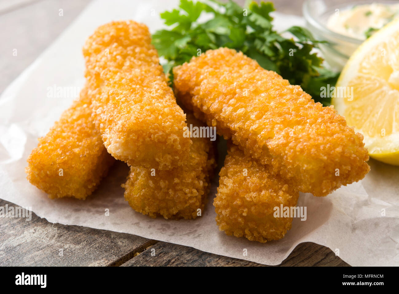 Les doigts de poisson frit croustillant avec du citron et de la sauce sur fond de bois Banque D'Images