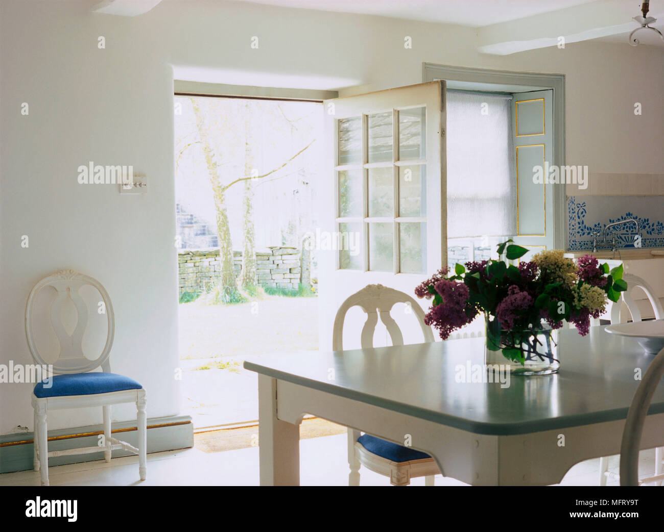 Un détail d'un pays blanc peint Gustavien table chaises Cuisine portes ouvertes Banque D'Images
