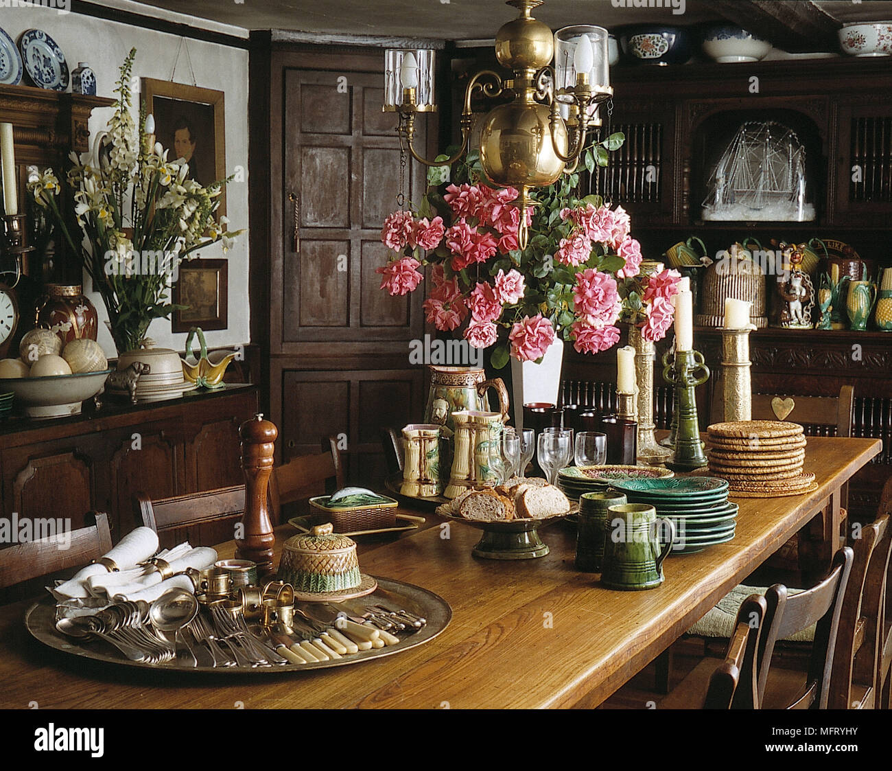 Salle à manger table de salle à manger frêne campagne victorienne chaises roses dans un vase vaisselle et couverts argenterie silver tray murs lambrissés en bois résineux Banque D'Images