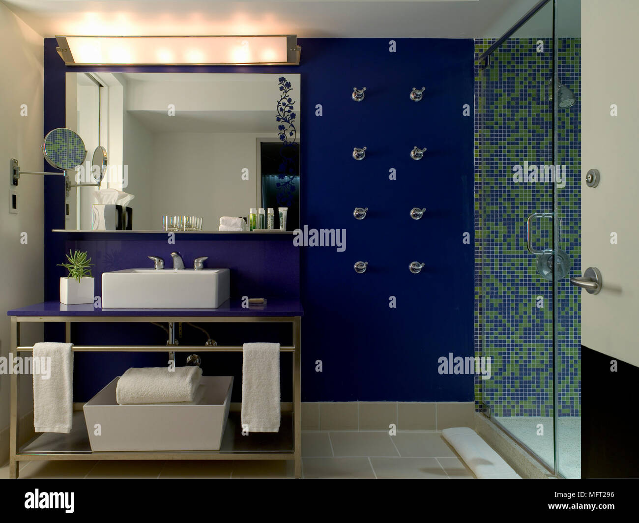 Salle de bains avec des murs carrelés et grand écran de douche en verre, lavabo et miroir en dessous de l'unité Banque D'Images