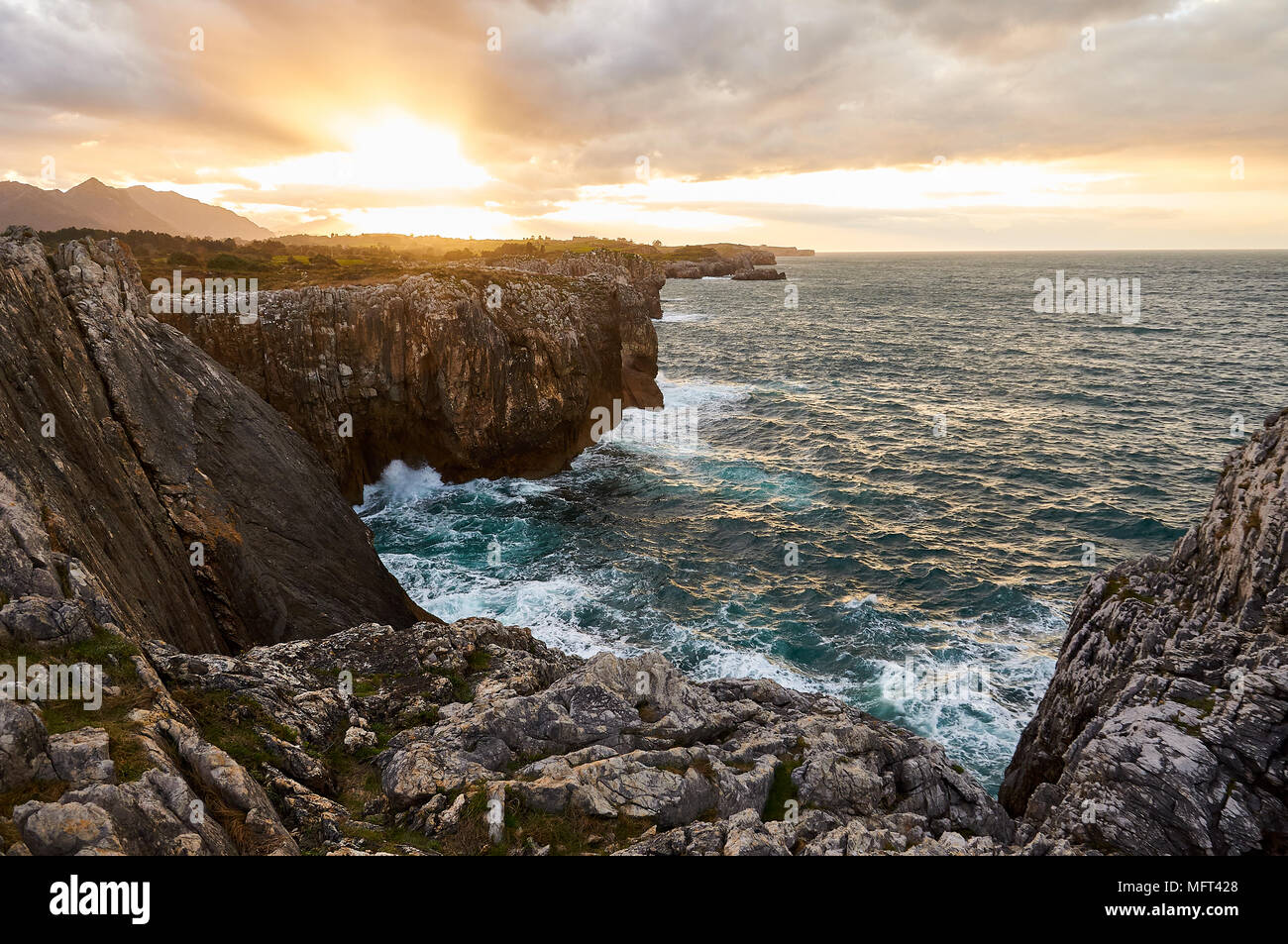 Vue panoramique sur la côte de mer de Cantabrie et les falaises au coucher du soleil nuageux près de la plage de Gulpiyuri (Naves, Llanes, Oriente, Asturies, Espagne) Banque D'Images