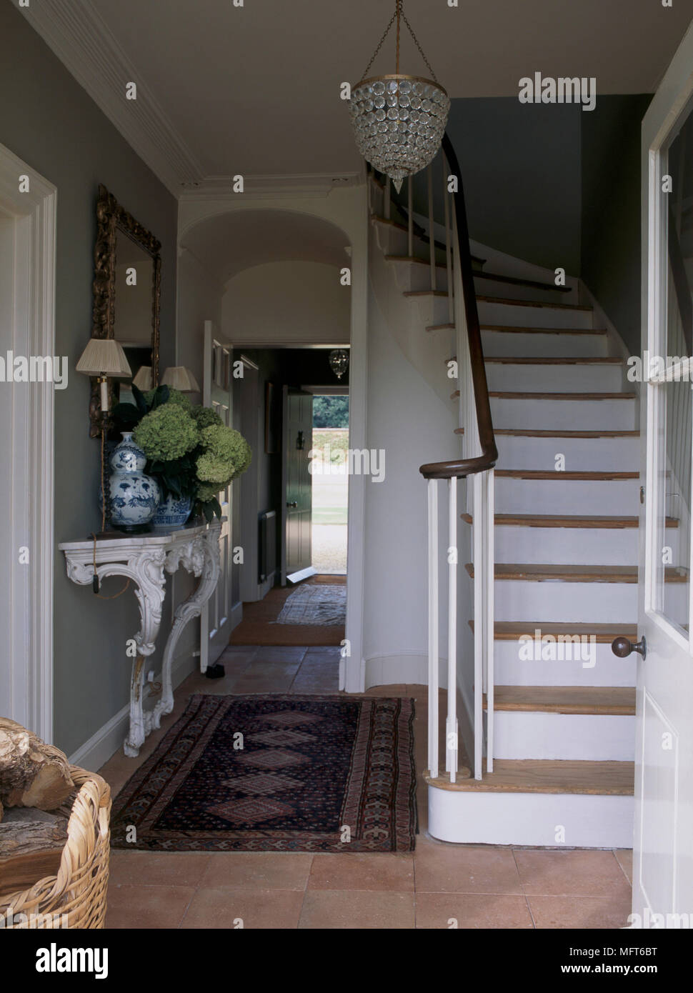 Un hall d'entrée avec porte vitrée demi ouvert, escalier en pierre, marbre,  lustre, table plateau ornementé Photo Stock - Alamy