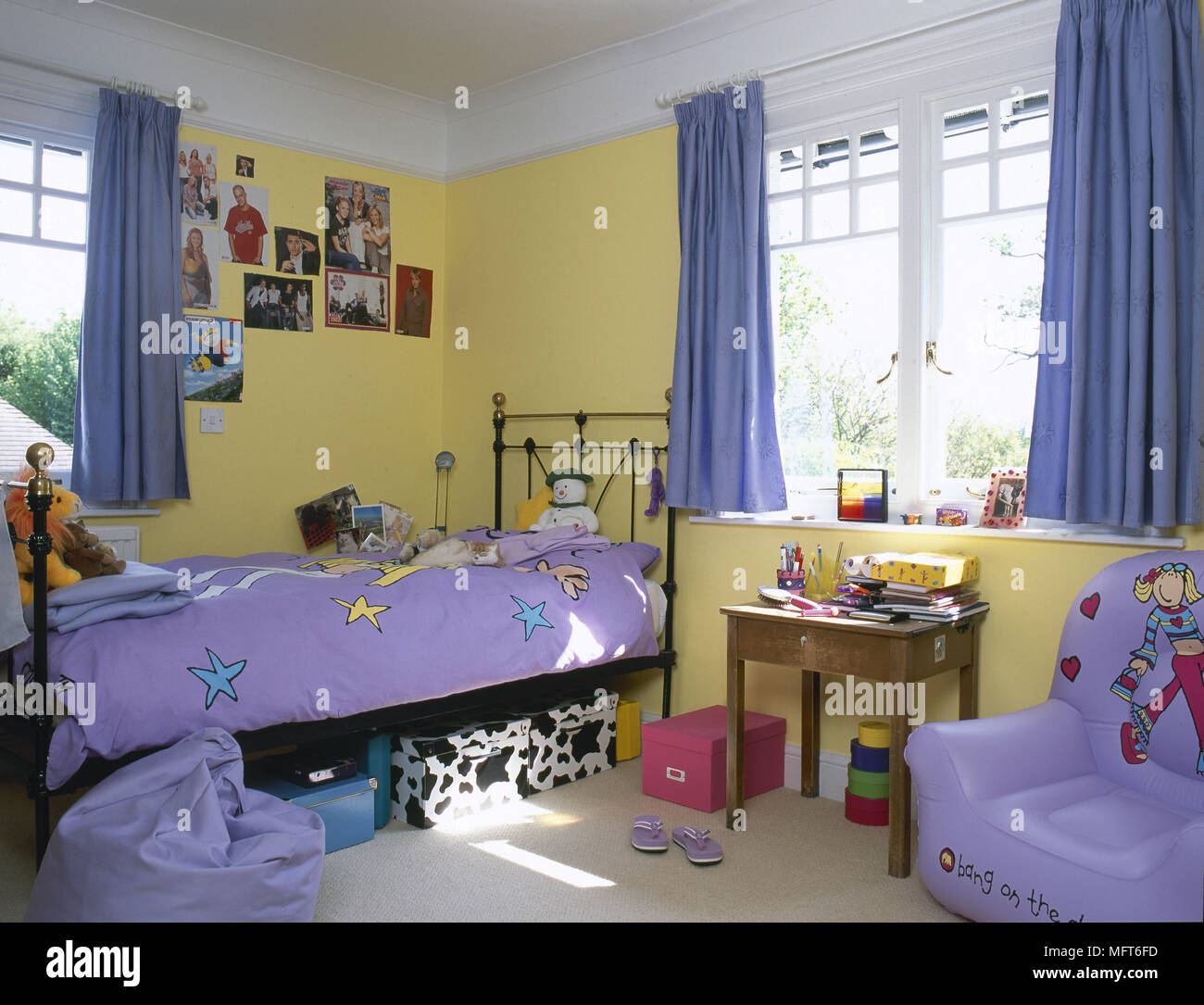 L'enfant, chambre à coucher avec lit en laiton jaune, rideaux bleus, table en bois, chaise gonflable, pourpre de la literie. Banque D'Images