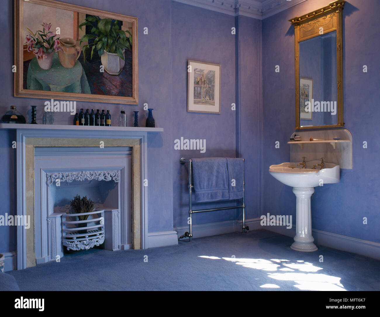 Bleu traditionnel, une salle de bains privative est équipée d'un lavabo, miroir doré, peint cheminée, et d'art encadrées. Banque D'Images