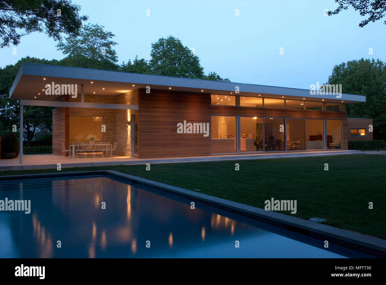 L'extérieur de nouveau construire maison de plain-pied avec piscine dans le jardin éclairé la nuit Banque D'Images