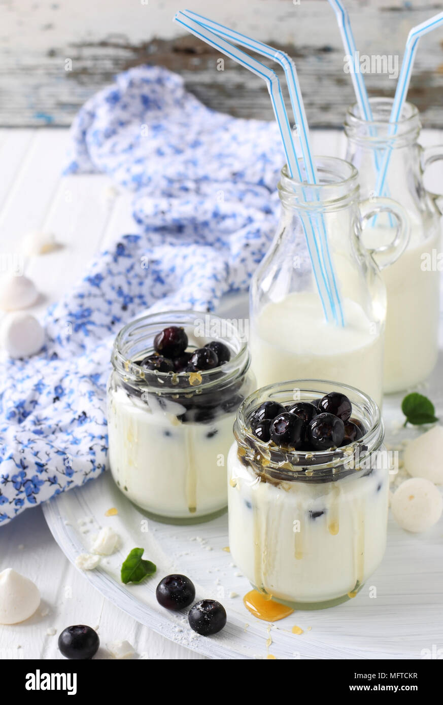 Du yaourt au miel et bleuets et lait en bouteille avec paille sur fond blanc Banque D'Images