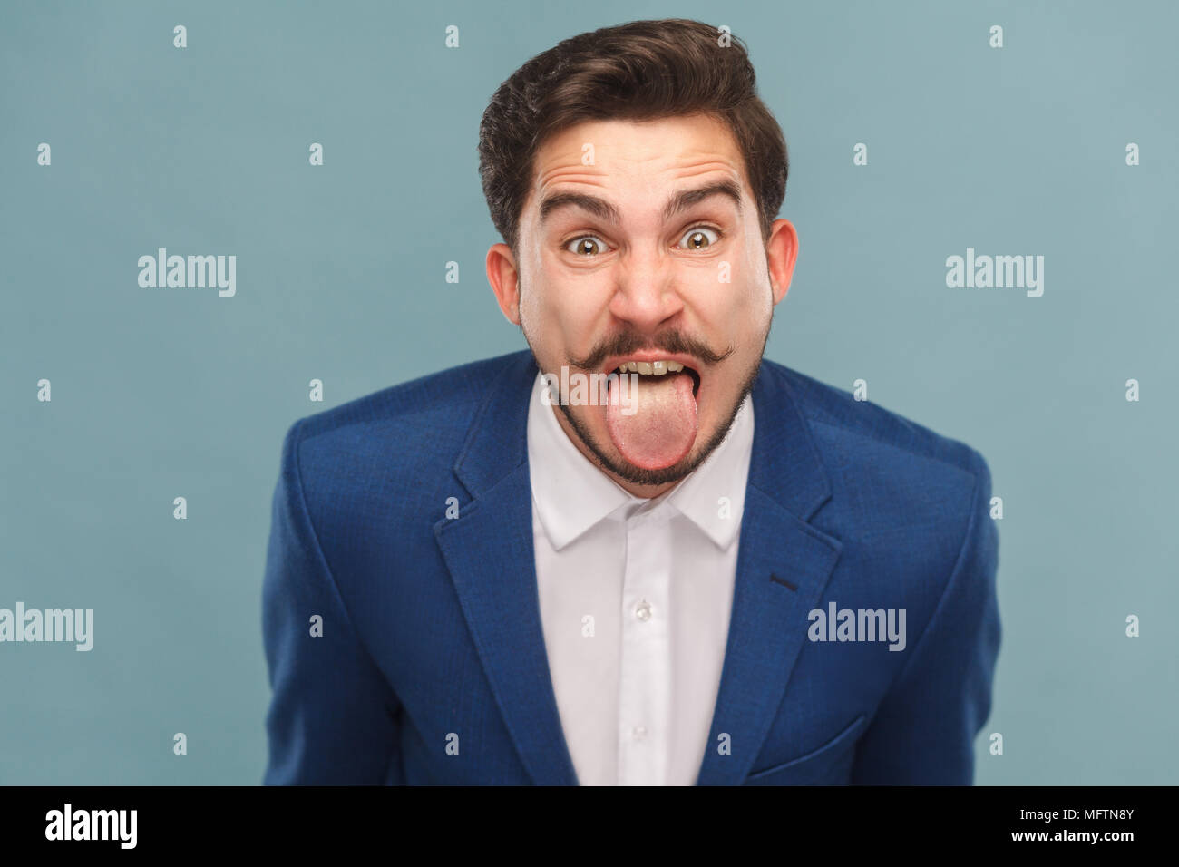 Portrait d'homme avec de grands yeux, de la langue et de crier. Les gens d'affaires, concept richement et succès. Piscine, studio shot sur fond bleu clair Banque D'Images Portrait d'homme avec de grands yeux, de la langue et de crier. Les gens d'affaires, concept richement et succès. Piscine, studio shot sur fond bleu clair Banque D'Images