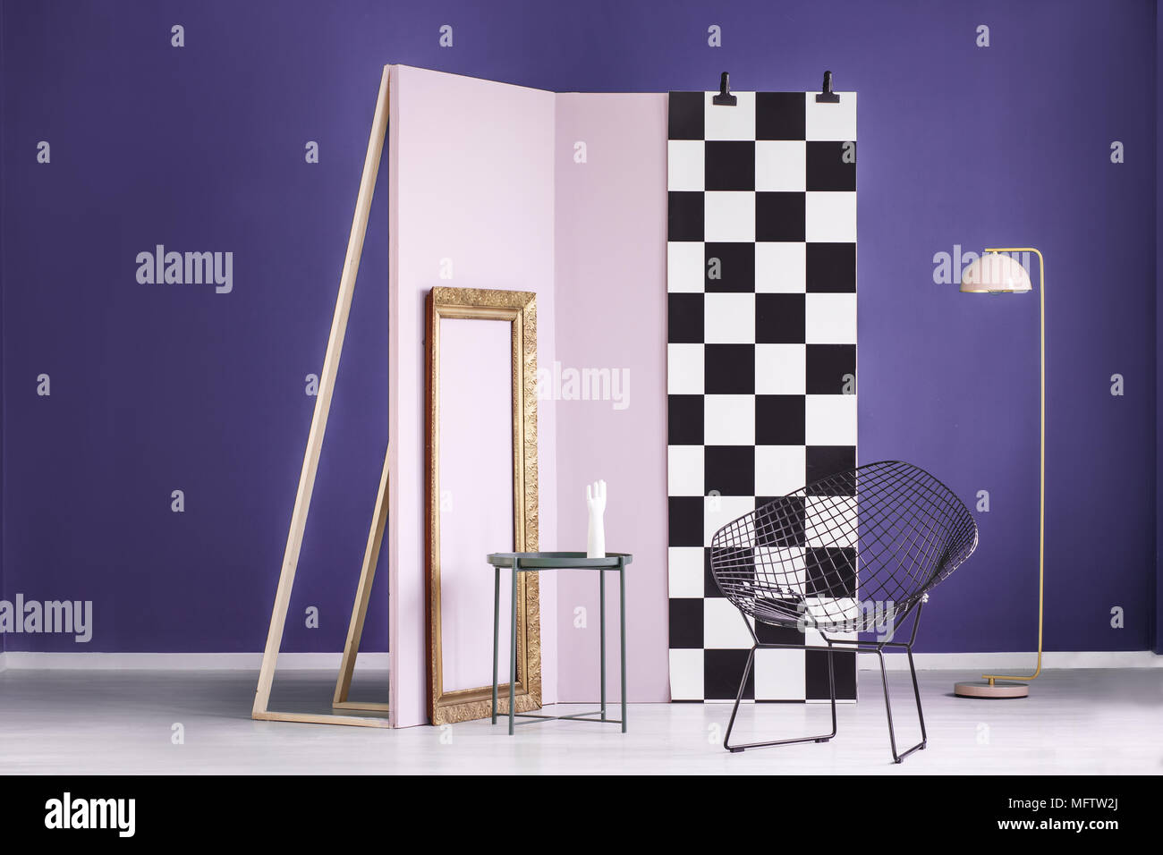 Photo réelle d'une installation artistique dans un cadre doré à l'intérieur violet, rose et noir, mur en métal chaises Banque D'Images