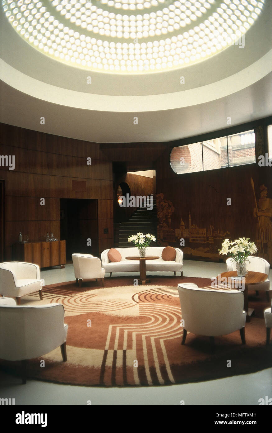 De style moderne, déco salon avec murs en courbe, une coupole circulaire avec lucarne, meubles capitonnés, et une table ronde, des tapis. Banque D'Images