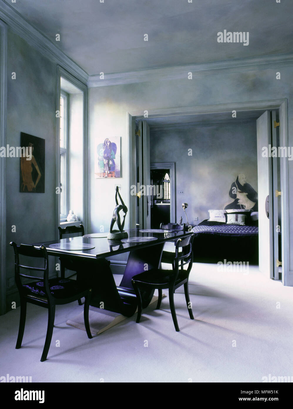 Espace ouvert moderne avec une table à manger et chaises sculpturales peinture décorative et de traitement ouvert portes pliantes pour une chambre adjacente. Banque D'Images