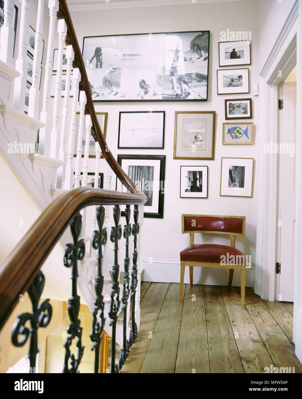 Escalier traditionnel avec l'atterrissage en détresse balustrades métalliques plancher et une chaise sous un affichage des illustrations encadrées. Banque D'Images