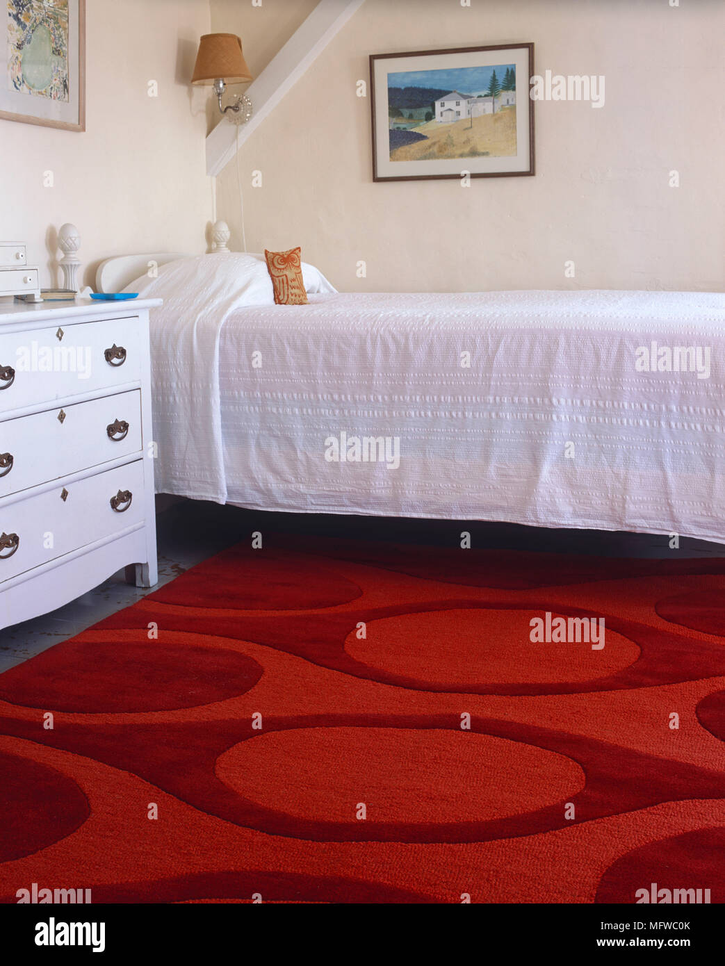 Commode blanche à côté d'un lit simple dans la chambre à coucher avec tapis  rouge Photo Stock - Alamy