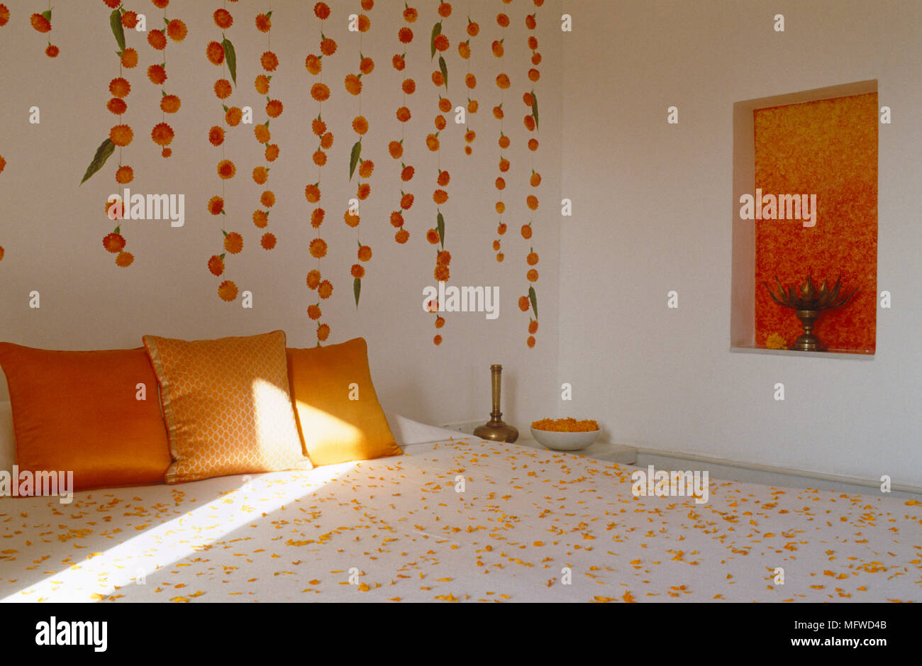 Coussins d'Orange sur un lit double avec effet peinture sur mur derrière Banque D'Images