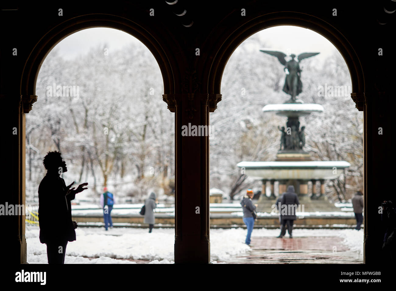 Manhattan à New York City Easter snow couvre Grand Central Park, Fontaine Bethesda par Bethesda exposée à un musicien ambulant chante pour les touristes tips Banque D'Images